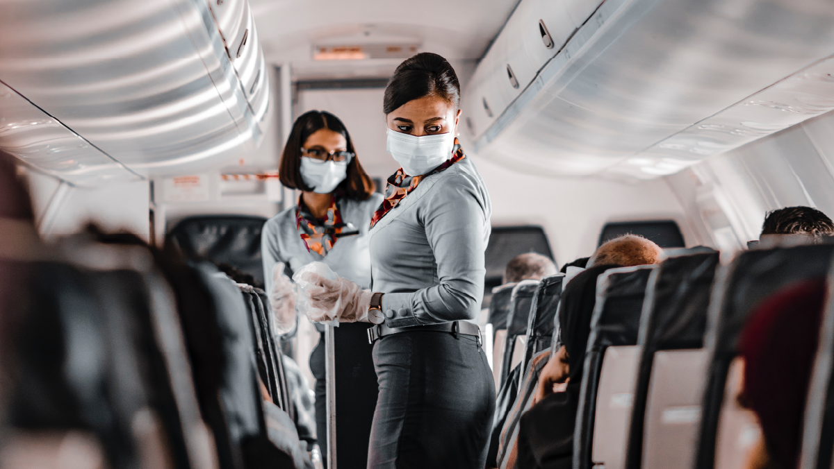 Flight attendants wear masks on a plane